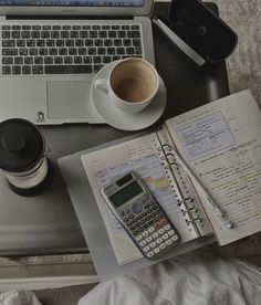 an open notebook, calculator and coffee on a desk