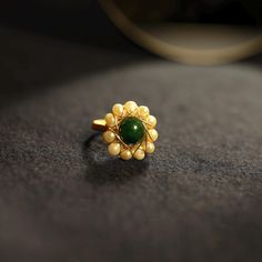 This exquisite 14K gold ring showcases a stunning green jade centerpiece, beautifully framed by delicate pearls in a floral design that exudes elegance and sophistication. Perfect as a statement piece for special occasions or adding a touch of luxury to everyday wear.✨ - Crafted from high-quality 14K gold, hypoallergenic and long-lasting - Features a natural green jade stone, symbolizing peace and harmony - Accented by pearls, arranged in a delicate floral-inspired pattern - Handcrafted with meticulous attention to detail, ideal for special events - A timeless and versatile accessory for women seeking unique, stylish jewelry - Perfect gift for birthdays, anniversaries, engagements, or holidays Ring Elegant, Design Statement, Jade Stone, 14k Gold Ring, Green Jade, Stylish Jewelry, Jade Green, Ring Handmade, Pearl Ring