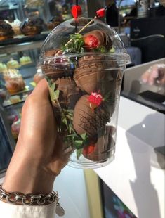 chocolate covered strawberries in a plastic container with chain around the wrist and red berries on top