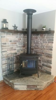 a wood burning stove sitting on top of a wooden floor next to a brick wall