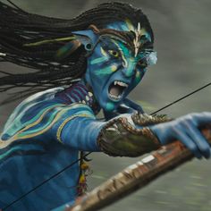 a woman with painted face and body is holding a bow in her hand while wearing blue paint