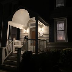 a house lit up at night with lights on the porch and steps leading to it