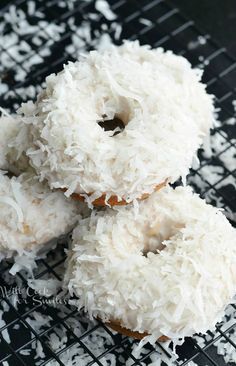 three coconut covered donuts on a cooling rack