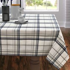 a table with a plaid cloth on it in front of a window and some flowers