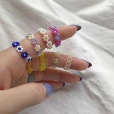 a woman's hand with five different colored rings on her fingers, all decorated with flowers