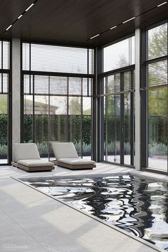 two chaise lounges in front of an indoor swimming pool with glass doors and windows