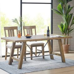 a dining table with chairs and a bottle of wine on it in front of a window