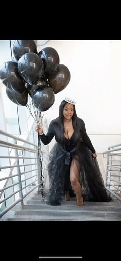 a woman in a black dress is holding some balloons