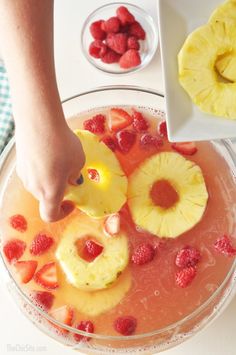 someone is squeezing fruit into a glass bowl