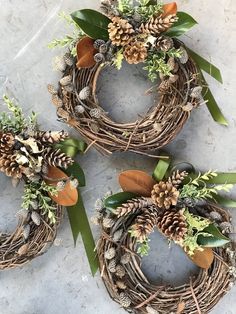 three wreaths with pine cones and greenery