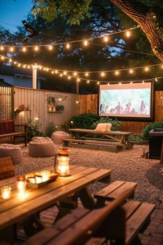 an outdoor movie is set up in the back yard with lights strung from the trees