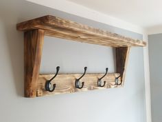 a wooden shelf with three hooks on it