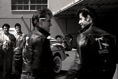 black and white photograph of men in leather jackets talking to each other on the street