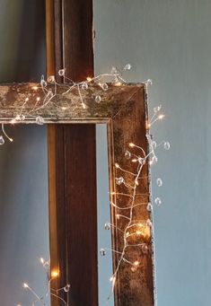 a mirror that has some lights on it and is next to a wall with a wooden frame