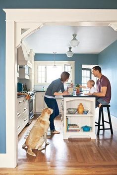 two people and a dog in a kitchen