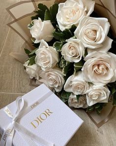 a bouquet of white roses sitting next to a box with the word dior written on it