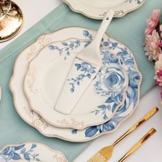 the table is set with blue and white plates, silverware, and pink flowers