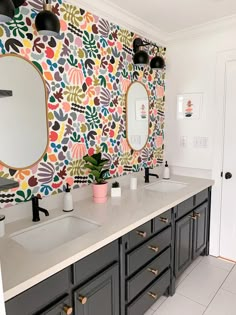 a bathroom with two sinks, mirrors and wallpaper on the walls in different colors