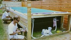 two men working on an above ground pool in the back yard with wood fence around it