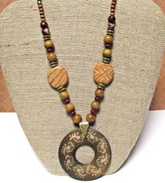 Wood Pendant Necklace on Waxed Linen Cord  16 to 21 inches (or shorter on request) with 2 inch round pendant They say if you can remember the Sixties, you weren't there. But I was there, and I do remember the fabulous, fun, tribal style jewelry that was popular then - and it's quite trendy today!  This red and brown pendant necklace features: * 2 inch round dark brown wood pendant covered with light tan symbols * anti-tarnish brass bail * dark brown waxed linen cord  * gorgeous golden tan Kazuri beads painted with white and red designs * wood beads in various sizes and tones * glass pearls in deep red * antiqued gold metal spacers * Nunn Design antiqued gold plated textured jump rings * gold plated chain * gold plated lobster claw clasp This bohemian jewelry can be worn at anywhere from 16 Bohemian Brown Beaded Round Necklaces, Bohemian Brown Beaded Necklace, Traditional Brown Beaded Necklaces For Gifts, Traditional Brown Beaded Necklace For Gift, Brown Round Bead Necklaces For Festivals, Traditional Brown Jewelry With Colorful Beads, Traditional Brown Beaded Necklace With Multicolored Beads, Traditional Brown Beaded Necklace With Colorful Beads, Brown Polished Beads Necklaces For Festivals