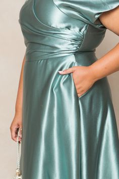 a woman in a green dress with her hand on her hip