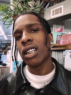 a man with dreadlocks wearing a black leather jacket and pearls on his necklace