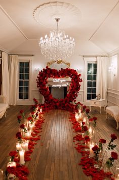 a long table with candles and roses on it in front of a mirror that is shaped like a heart