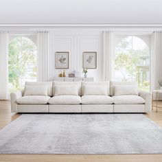 a living room with white couches and large rugs on the hardwood flooring