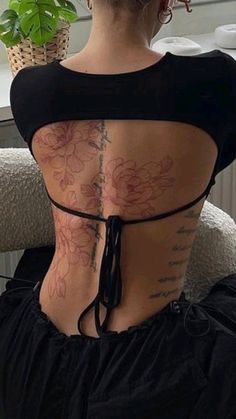 a woman with tattoos on her back sitting in a chair