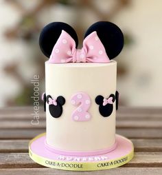 a minnie mouse cake is decorated with pink and white polka dots, ears, and a bow