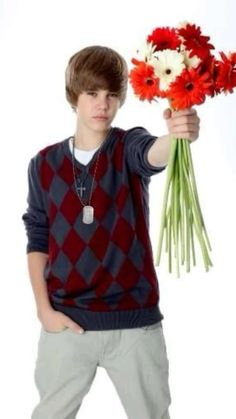 a young man holding flowers in his hand