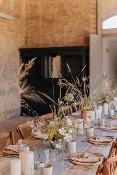 the table is set with place settings and flowers in vases, candles, and napkins