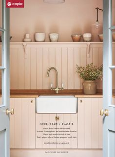 an open door leading to a kitchen with pink walls and white cupboards on the wall