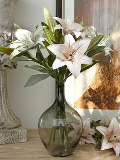 a vase filled with white flowers sitting on top of a wooden table next to a painting