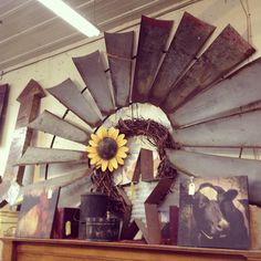 a sunflower is placed on top of an old windmill wheel in a room with other items