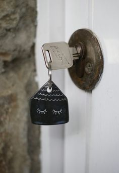 a door with a key hanging from it's side and a house shaped key holder attached to it