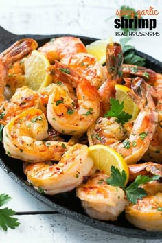 a skillet filled with cooked shrimp and lemon wedges, garnished with parsley