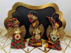 three african dolls are standing in front of a black and gold framed sign with golden trim