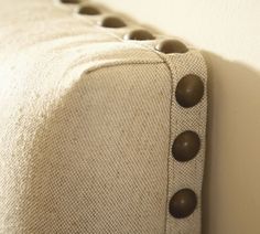 the back of a couch with buttons on it's arm and fabric linings