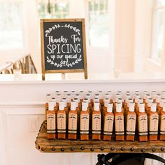 there are many bottles of hot sauces on the table with a sign in the background