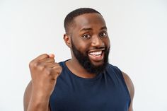 a man with a beard and blue tank top is making a fist gesture to the camera