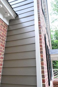 the side of a house with a brick wall and white gutter on the roof