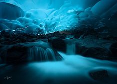 an ice cave with water flowing down it's sides and rocks in the foreground