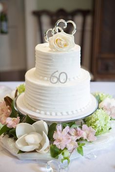 a white wedding cake with flowers on the side and a couple's initials on top