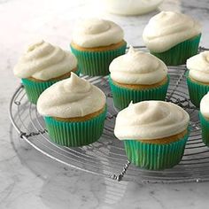 cupcakes with white frosting sitting on a cooling rack