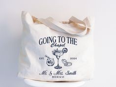 Celebrate your special day with our "Going to the Chapel" Tote Bag collection, designed to make your wedding preparations as beautiful and seamless as your ceremony. Order now and make your wedding preparations a cherished part of your love story! Tote Bag Details: * 12.0 oz., 100% heavy cotton canvas * Large main compartment with zippered closure * Inside zippered flap pouch pocket * 25" self-fabric handles * 11" handle drop * 20"X x 15"H x 5"D Maid of Honor Gift - MOH Gifts - Maid of Honor Proposal - Maid of Honor Gifts - Bridesmaid Proposal - Bridesmaid Gifts - Bridesmaid Gift Box - Matron of Honor Gift - Matron of Honor Gifts - Will your be My Bridesmaids - Will you be my Matron of Honor - Will your my be Maid of Honor - Bridal Shower Gift - Bride to be Gift - Bride to be Gifts - Fathe Ceremony Order, Moh Gift, Bachelorette Tote Bags, Going To The Chapel, Bachelorette Tote, Engagement Gifts For Bride, Maid Of Honor Gift, Mother Of The Groom Gifts, Engagement Gifts For Couples