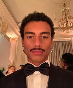 a man in a tuxedo and bow tie is looking at the camera with an intense look on his face