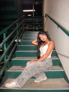 a woman sitting on some stairs with her hand on her head and looking at the camera