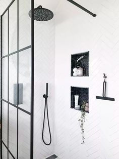 a bathroom with black fixtures and white tiles on the walls, including a shower head