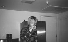 black and white photograph of a boy drinking from a glass in front of an open refrigerator